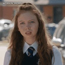 a girl with long red hair is wearing a workin ' moms shirt