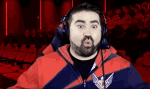 a man with a beard wearing headphones is making a funny face in front of a crowd .