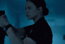 a woman in a police uniform is holding a gun in her hand in a dark room .