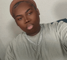 a young man wearing a headband and a chain around his neck takes a selfie