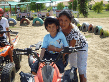 a woman stands next to a boy riding a four wheeler that says ma-015