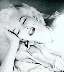 a black and white photo of a woman laying down with her eyes closed