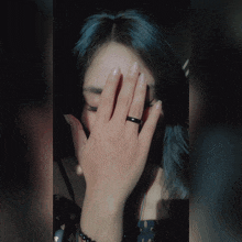 a woman with a black ring on her finger is covering her face