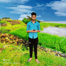 a man in a blue shirt and fila pants stands in a grassy field