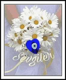 a person holding a bouquet of daisies with a blue heart and the word sevgilir written on the bottom