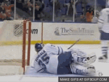 a hockey goalie is laying on the ice in front of a sign that says " the smile team "