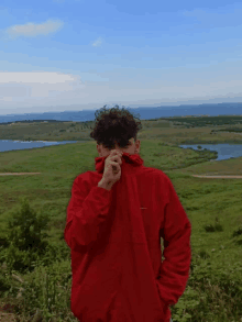 a man in a red jacket is covering his face with his hand