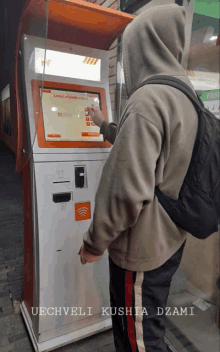 a man in a hoodie is using a machine that says uechveli kushia dzami