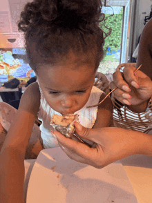 a little girl eating a piece of food with a toothpick in her mouth