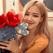 a woman in a yellow shirt is holding a vase of flowers and smiling