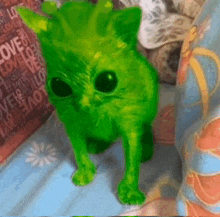 a green cat is sitting on a bed with a sign that says love on it