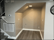 a corner of a room with stairs and a thermostat on the wall