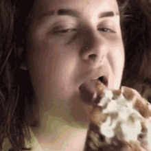 a woman with long hair is eating a waffle with whipped cream