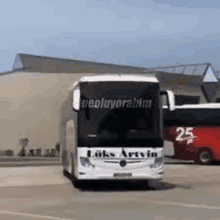 a white bus is parked in front of a building on a highway .