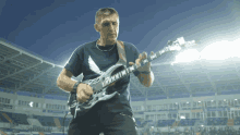 a man playing a guitar in a stadium with a shirt that says maximum