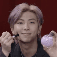 a man with purple hair is smiling while applying makeup