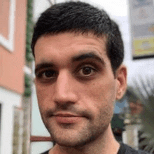 a man with a beard and a black shirt is looking at the camera .