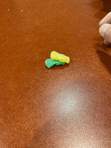 a person reaches for a green and yellow gummy bear