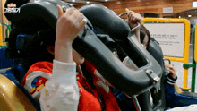 a woman in a red shirt is riding a roller coaster with a sign that says ' warning ' on it