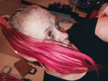 a woman with pink hair and a black shirt is laying down