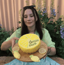 a woman holding a cake that says lemon cute