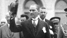 a black and white photo of a man in a suit and tie holding a hat