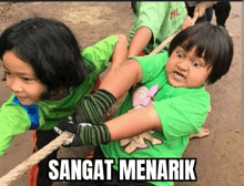 a group of children are playing tug of war and the caption sangat menarik