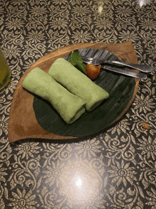 two green rolls on a banana leaf on a plate