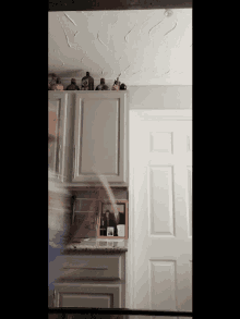 a kitchen with white cabinets and bottles on the shelf including one that says ' tequila '