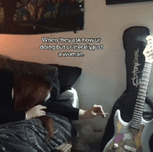 a woman laying on a bed next to a guitar that says epiphone on it