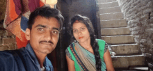 a man and a woman pose for a picture in front of some stairs