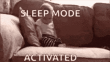 a baby is laying on a couch with the words `` sleep mode activated '' above it .