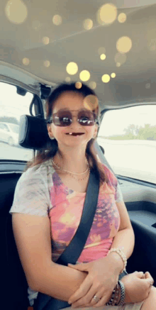 a woman wearing sunglasses and a pearl necklace is sitting in the back seat of a car