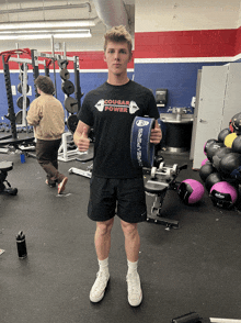 a man in a black shirt that says cougar power holds a dumbbell