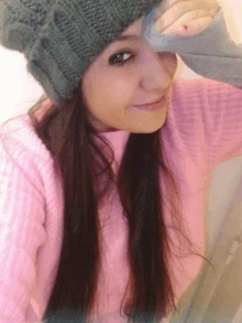 a woman wearing a pink sweater and a grey hat