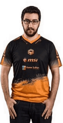 a man with glasses and a beard is wearing a black and orange msi shirt .