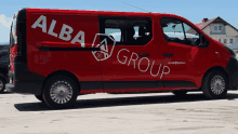 a red van with alba group written on the side is parked in a parking lot