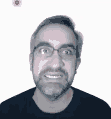 a man with glasses and a beard is smiling with a red dot in the background