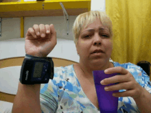 a woman is holding a purple cup and wearing a microlife blood pressure monitor