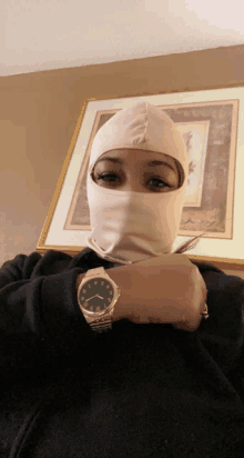 a woman wearing a ski mask has a watch on her wrist with the hands on the numbers 1 and 12