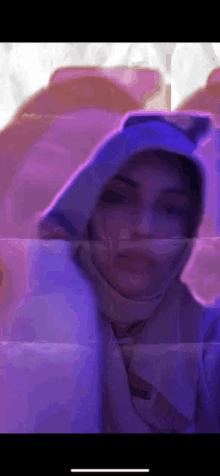 a woman wearing a hoodie and a scarf is taking a picture of herself .