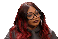 a woman with red hair is wearing glasses and a gray sweater