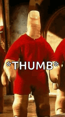 a person with a large finger on their head is wearing a red shirt and shorts and giving a thumbs up .