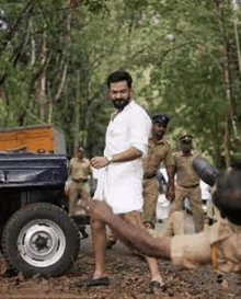 a man in a white shirt and shorts is standing in front of a jeep .