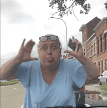 a woman in a blue shirt is making a funny face while holding a cell phone