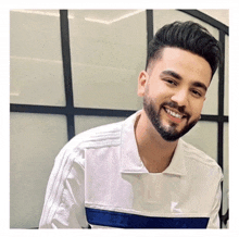 a man with a beard wearing a white shirt and smiling