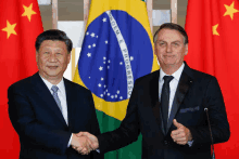 two men shaking hands in front of a flag with the word progresso on it