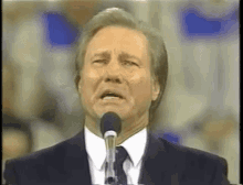 a man in a suit is singing into a microphone .