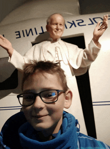 a boy wearing glasses is standing in front of a statue of a man with the word time on it