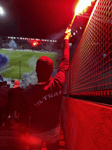 a person wearing a shirt that says ultras holds up a flare